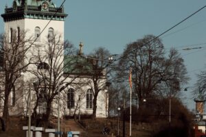 I bilden visas en vacker, vit kyrka med en grön takpälsning och en klocktorn. Det finns också nakna träd omkring och några elektriska ledningar. Liksom kyrkan lätt fångar blickens uppmärksamhet, kan du bygga ditt varumärke visuellt på Instagram i Sverige. Använd vackra bilder, unika designs och engagerande videor för att göra ditt varumärke märkbart och minnesvärt bland svenska användare.